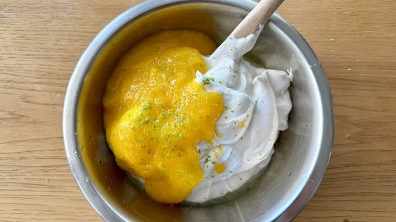 whipped cream and pureed mango in metal bowl