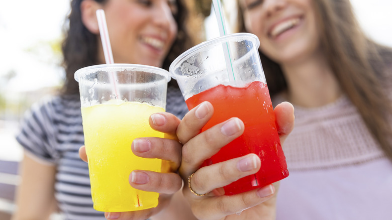 Two women holding plastic cups filled with a slushy beverage