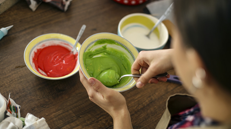 A woman mixes food dye in bowls