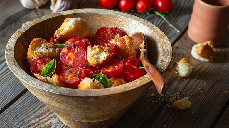 Wooden bowl with sliced cherry tomatoes, basil, and toasted bread