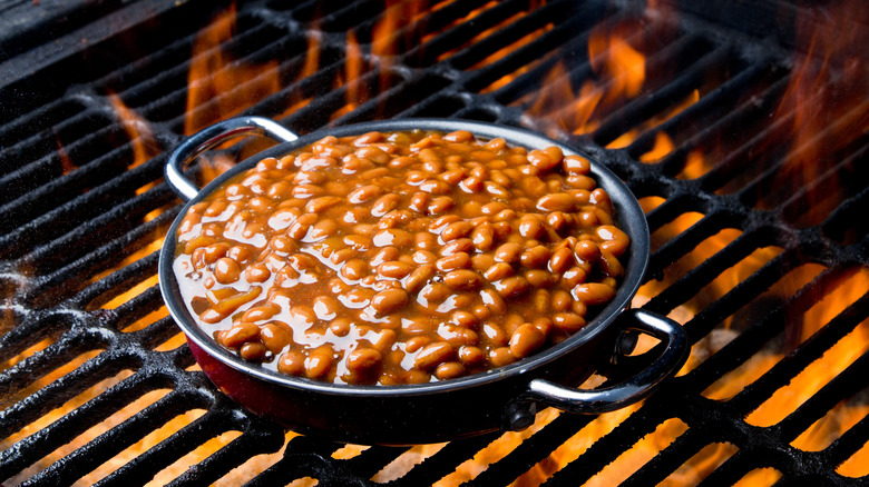 Baked beans in a skillet on a flaming grill