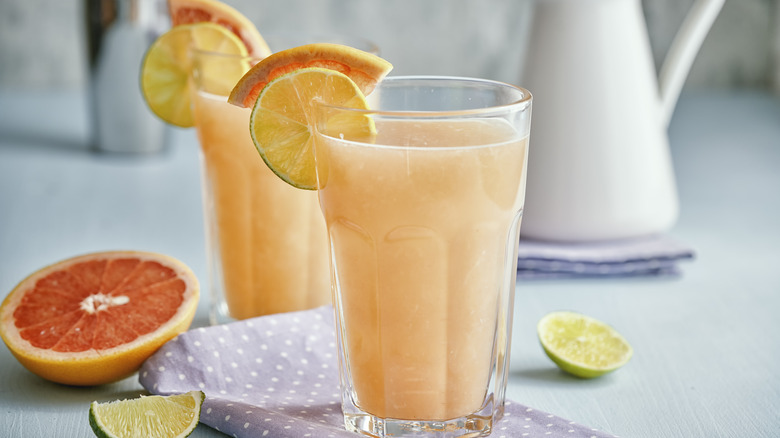 Two paloma cocktails with sliced grapefruit and limes