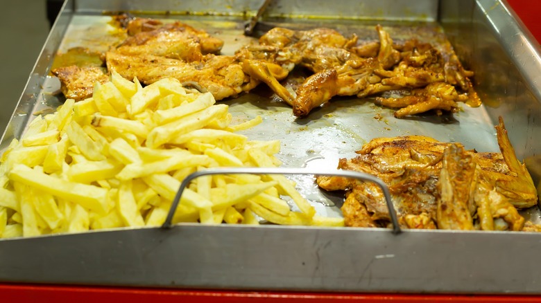 Person cooking fries and chicken on the grill