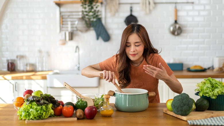 Woman smelling a pot of food