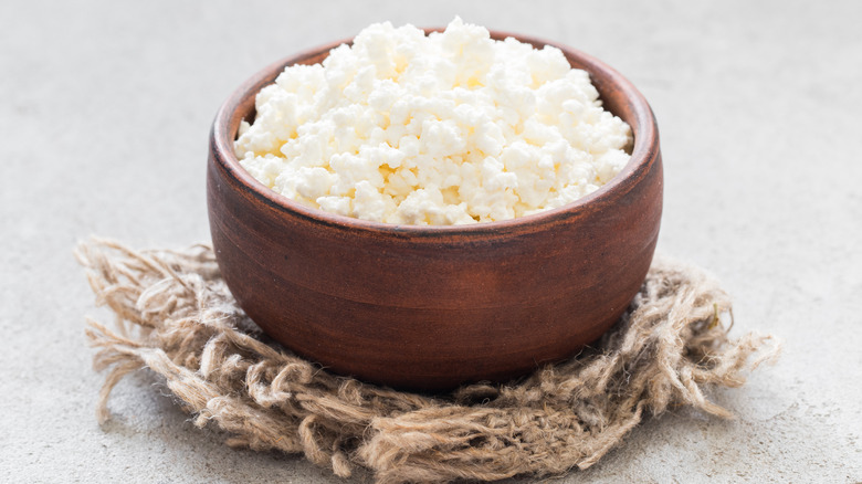 A brown wooden bowl containing cottage cheese