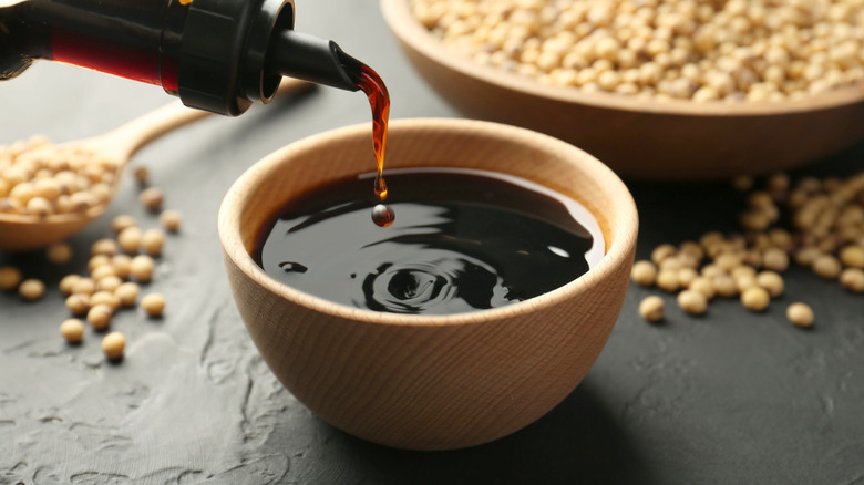 Soy sauce pouring from bottle into small bowl