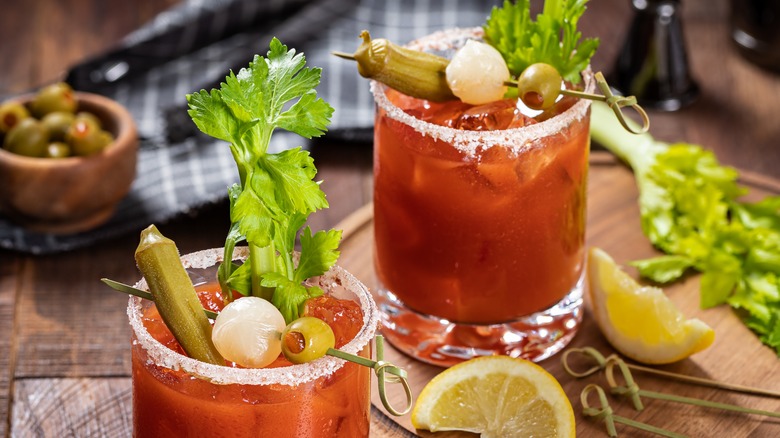 Two bloody Marys garnishes with green olives, celery, and pickled vegetables