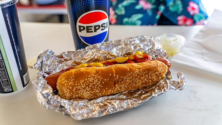 Costco hot dog in foil next to Pepsi fountain drink