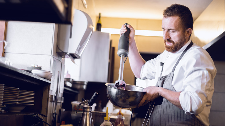 A chef using an immersion blender