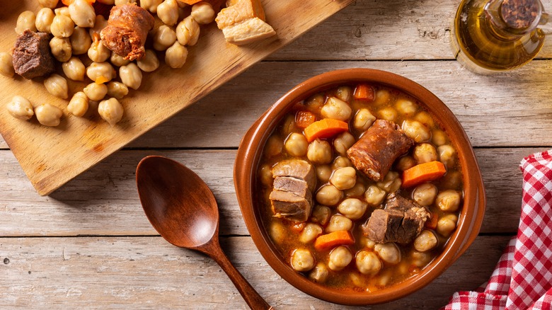 Bowl of cocido madrileño on a wooden table.