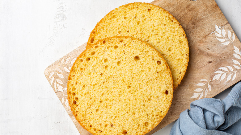 Two round, airy slices of sponge cake on a wooden cutting board