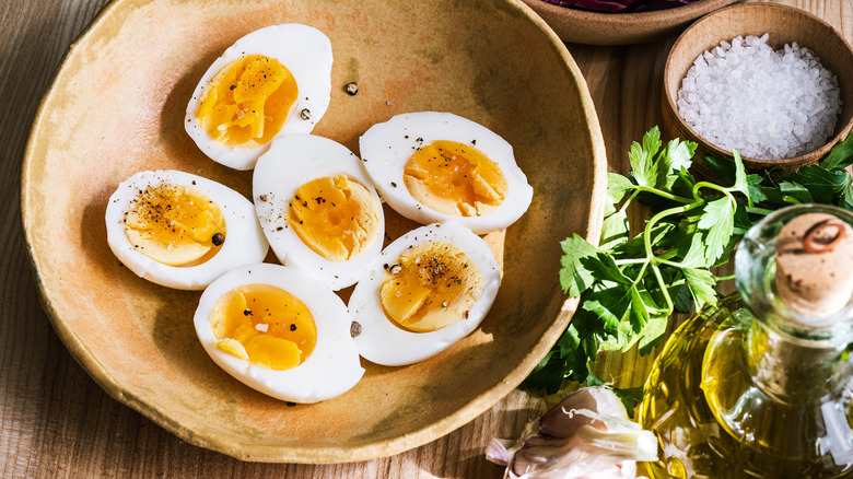 Boiled eggs in bowl with bottle of olive oil