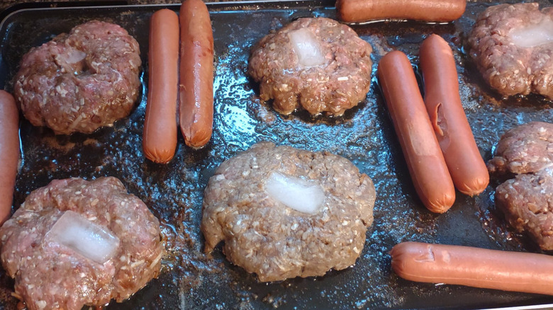 burger patties with ice cubes and hot dogs on grill
