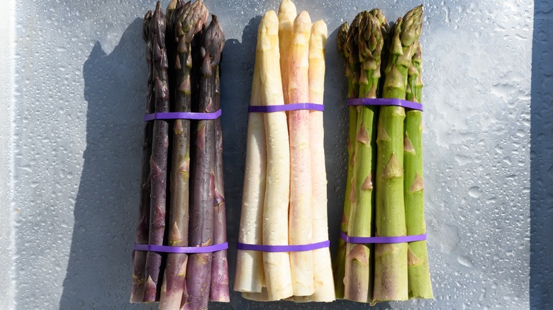 Purple, green, and white asparagus on a tray