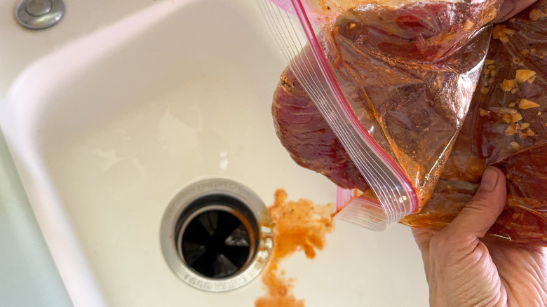 Draining marinade from ziplock bag with flank steak into sink