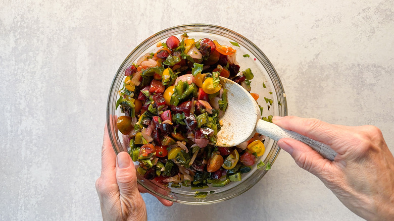 Mixing stone fruit salsa in glass bowl with wooden spoon on countertop