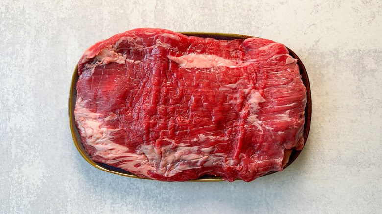 Raw flank steak on plate on countertop