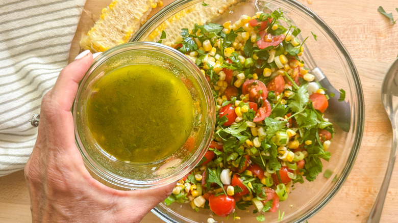 hand adding dressing to salad