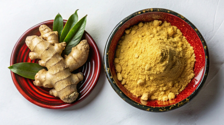 Fresh ginger root and powdered ground ginger in bowls