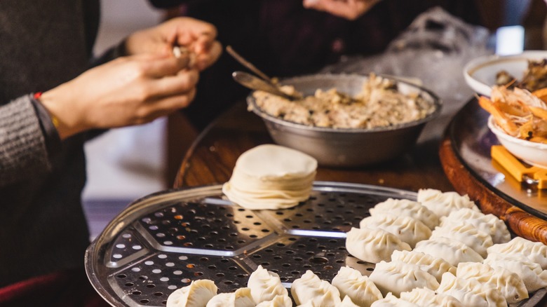 Two people making dumplings for a crowd.