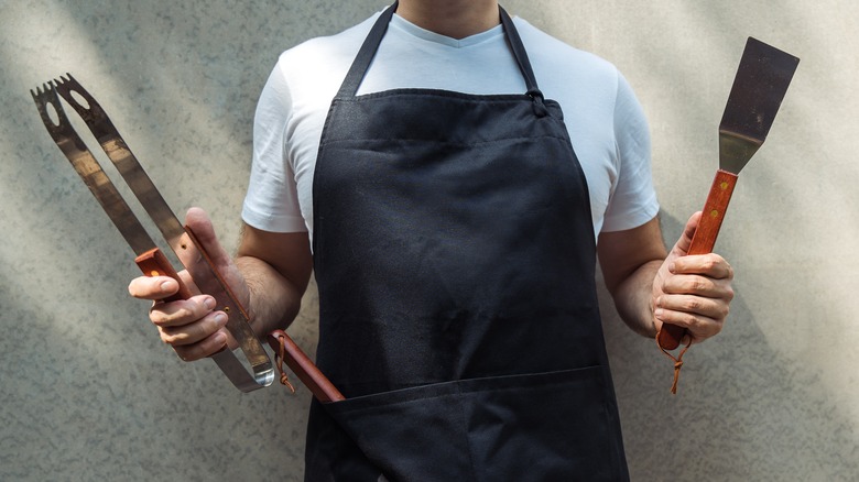 Man holding utensils for grilling