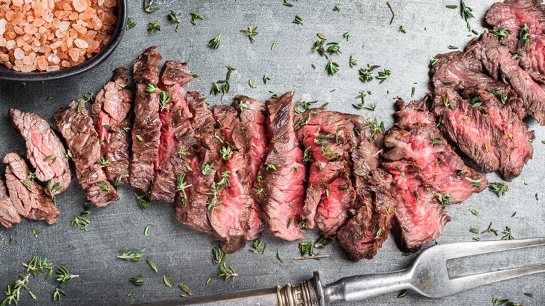 Sliced grilled skirt steak on a gray background