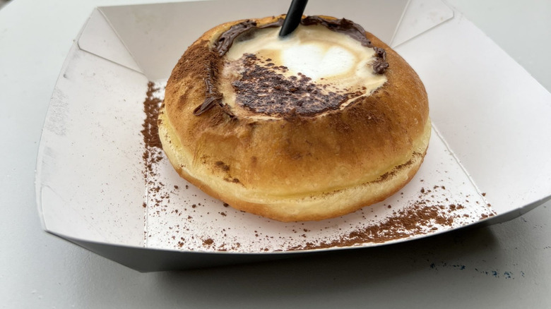Latte served in a donut topped with cocoa powder