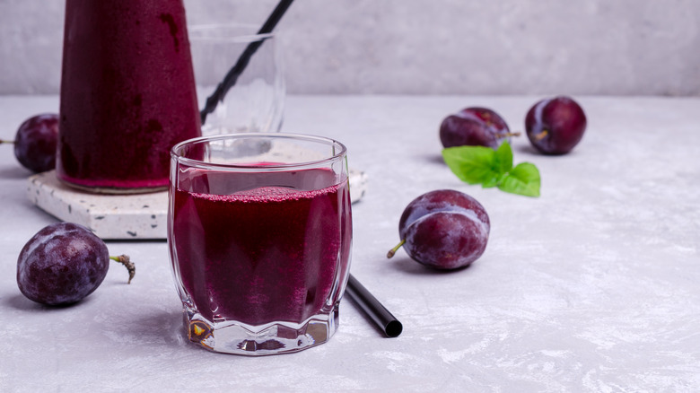 Glass of prune juice next to prunes