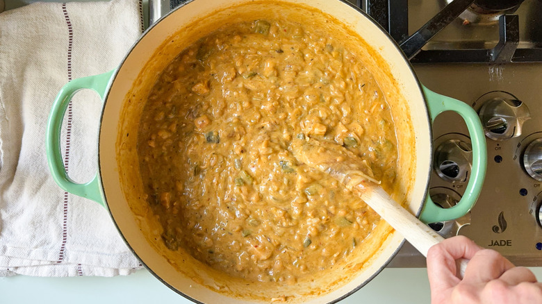 Hearty white chicken and navy bean chili in large pot on stovetop with wooden spoon