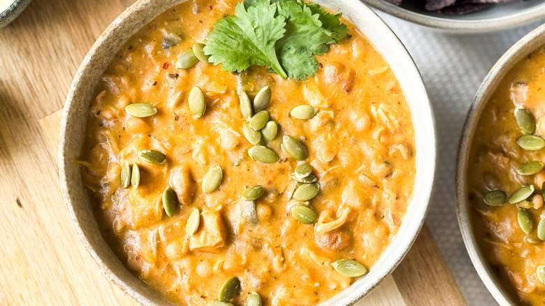 Hearty white chicken and navy bean chili in bowls with cilantro and pepita garnish