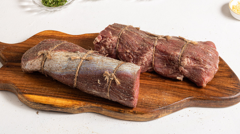 Two sliced of seasoned beef tenderloin with cooking thread around the meat