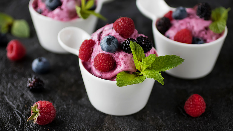 a cup of berry sorbet topped with fresh berries and a sprig of basil