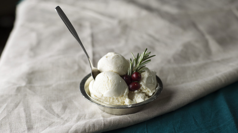 a small bowl of vanilla ice cream topped with a sprig of rosemary