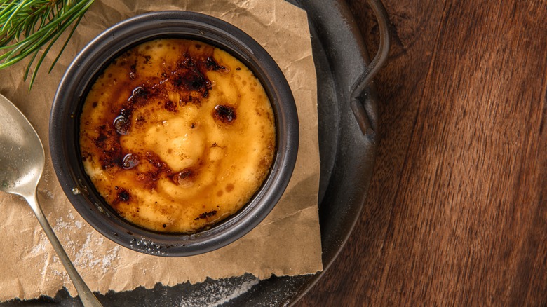 a ramekin of creme brulee sits on a dark table