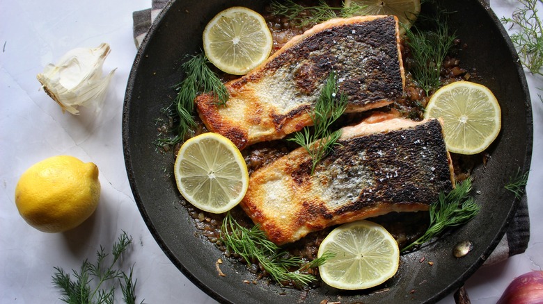 skillet with salmon fillets, lemons, and dill