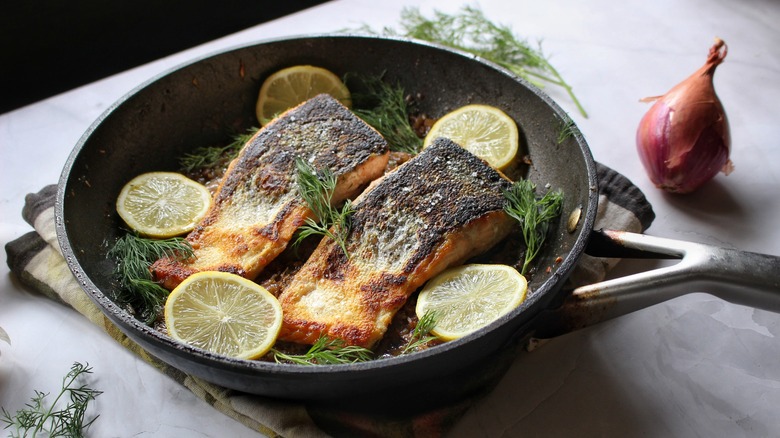 skillet of salmon with lemon slices and dill fronds
