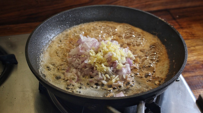 skillet of melted butter with shallots and garlic