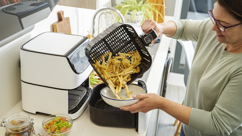 Person dumping air fried potatoes into bowl