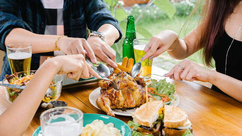 Group of people sharing a whole roasted chicken