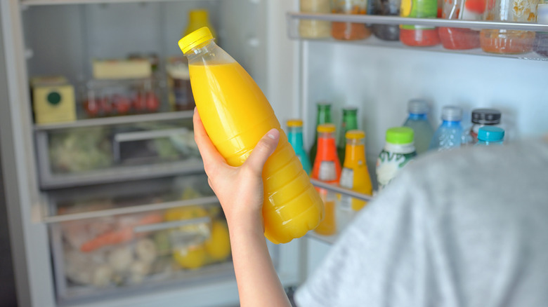 Person taking a bottle of OJ out of the fridge