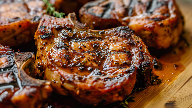 A marinated pork chop on a rustic wooden board.