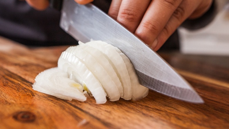 hands slicing an onion