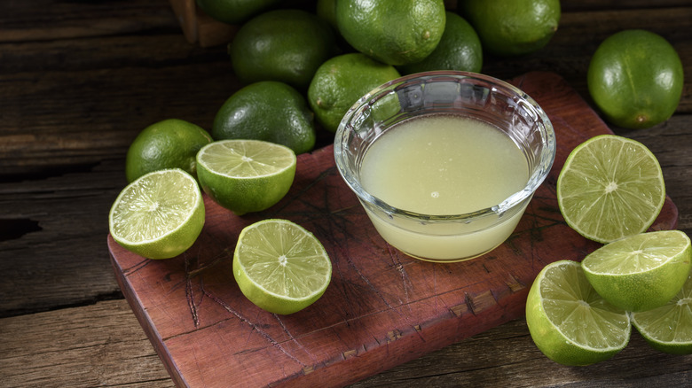 bowl of lime juice with limes surrounding it