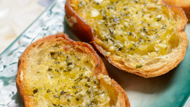 Crispy, sliced, buttery garlic bread hot out of the oven full of herbs and spices.