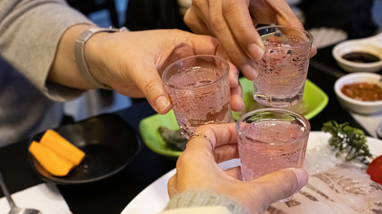 three people toasting soju glasses