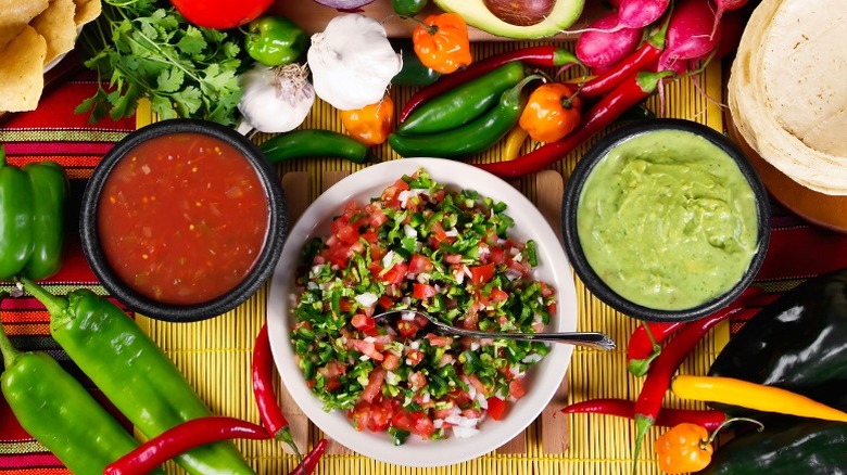 Mexican ingredients and salsas are displayed on a brightly colored cloth.