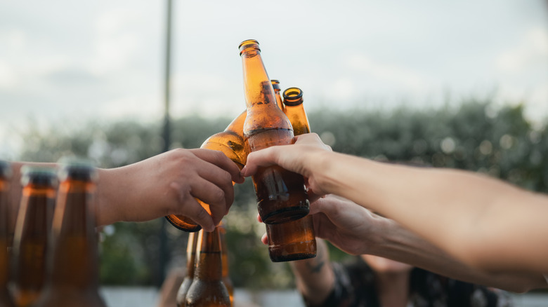several people clinking beers