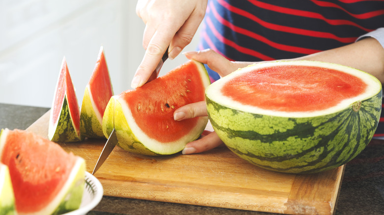 person slicing into watermelon