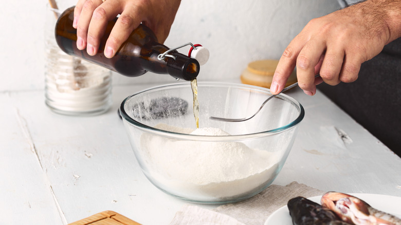 Hands pouring beer into a bowl of beer batter