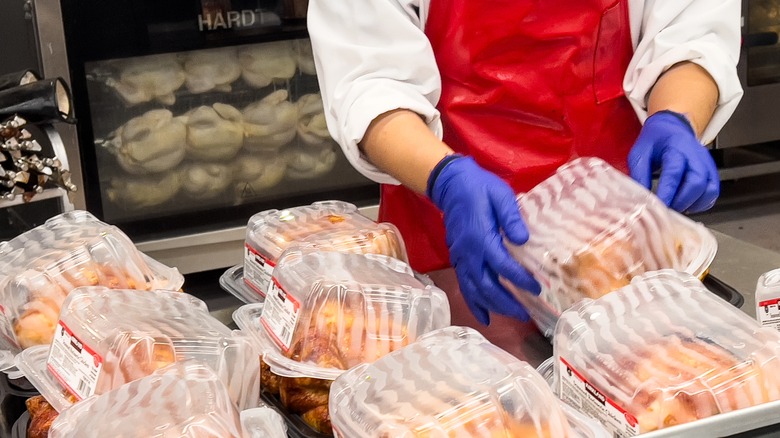 Person handling Costco rotisserie chicken